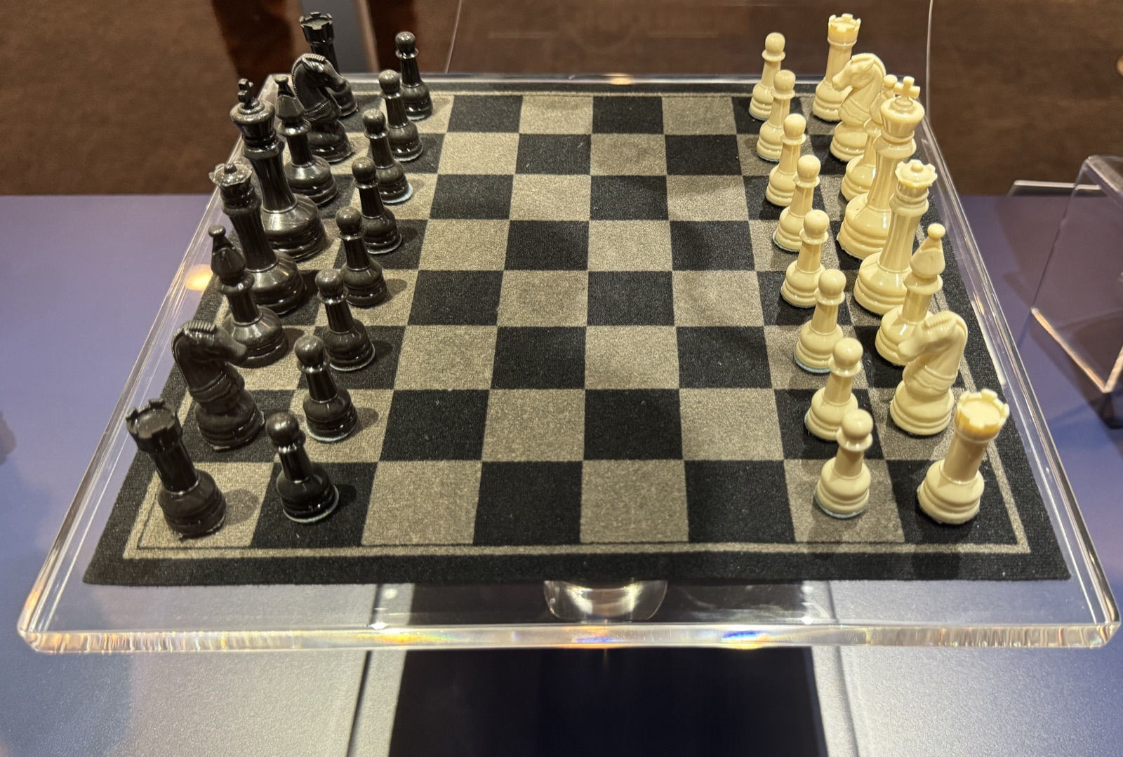 A chess set on a glass board in the starting position