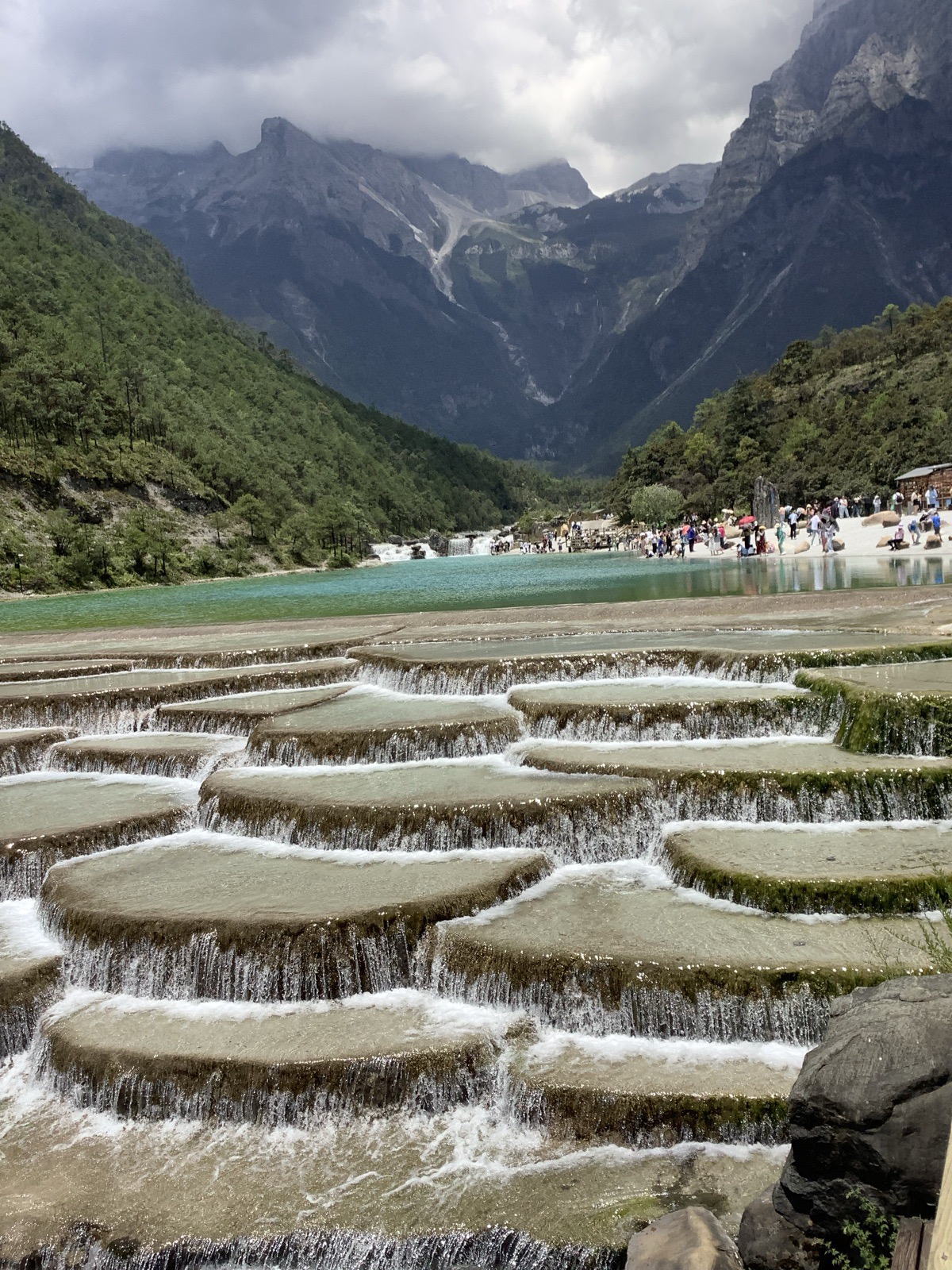 Terraced travertine pools stepping down below a snow-capped range