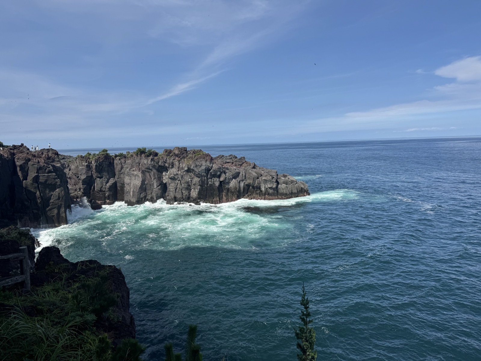 Waves breaking against dark volcanic sea cliffs